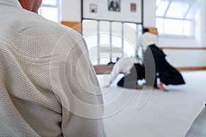 People practicing aikido in a dojo background.