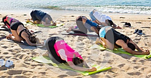 People practicing yoga on beach
