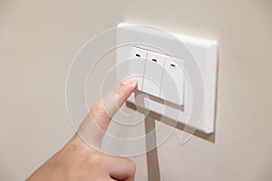 People press light switch to turn off the light for saving home energy reduce utilities billing cost