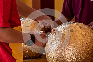 People put gold sheet stick-on sacred marker spheres that need to be buried in the temple compound