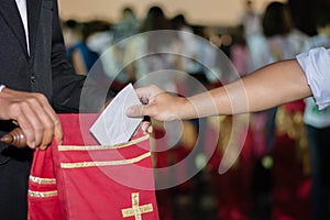 People putting tithing into Velvet offering bag in church