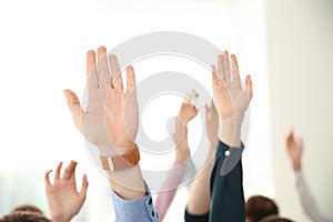 People raising hands to ask questions at business training on background, closeup