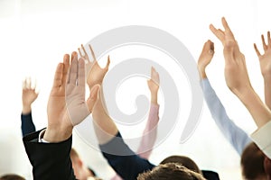 People raising hands to ask questions at business training on light background, closeup