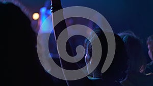 People raising their hands and singing songs. Silhouette of a girl dancing at a rock band concert. Live performance in a