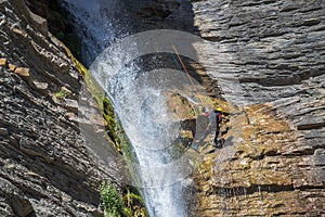 People rappelling in an impressive waterfall