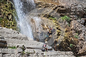 People rappelling in an impressive waterfall