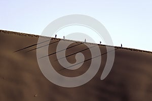 People on a red dune in the Namib Desert, in Sossusvlei, Namibia