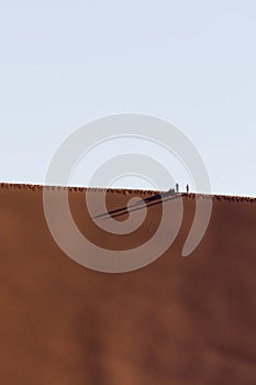 People on a red dune in the Namib Desert, in Sossusvlei, Namibia