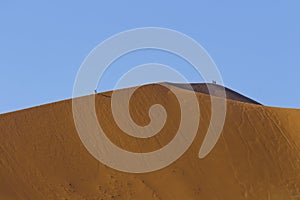 People on a red dune in the Namib Desert, in Sossusvlei, Namibia