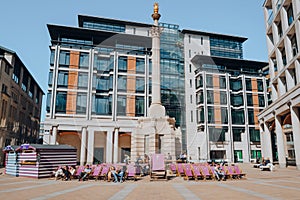 People relax on deck chairs at the Paternoster Square, City of London, UK