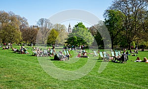 People relax in London St James Park with Big Ben seen in background