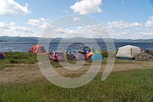 People relax in a tent camp on the shore of a Large lake in the summer season