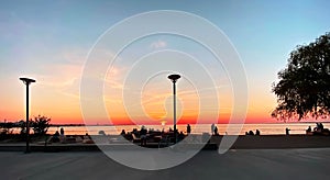 People relax and walk  at summer white night on  sea pier ,gold pink sunset on promenade ,horizon blue cloudy sky , city street la