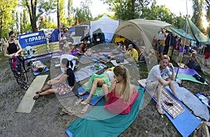 People relaxing around fest camp sitting lying on karemats. Festival Vedalife. Kyiv, Ukraine