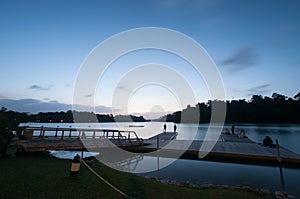 People relaxing on deck by lake in evening