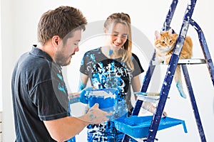 People, renovation, pet and repair concept - Portrait of lovely funny couple with cat doing redecoration in apartment photo