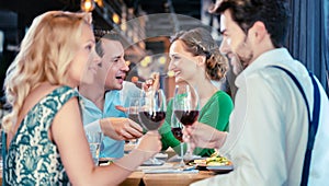 People in a restaurant eating and drinking red wine