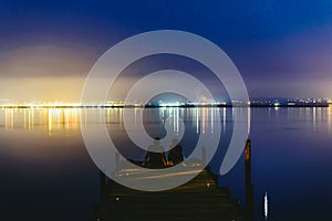 People resting relaxed on a pier on a lake at sunset with calm water