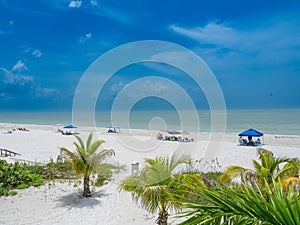 People resting on a sandy beach on a cloudy day in Estero Island, Florida