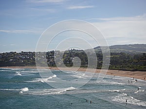 People resting on the sandy beach and swimming in the blue ocean in Kiama town on a sunny day