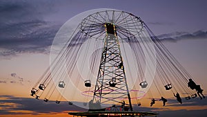 People ride on the chained carousel against twilight sky in evening: slow motion