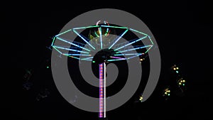 People ride on the chained carousel with illumination against dark sky at night