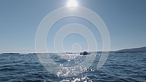 People ride a motor boat in the sea against the background of the sun