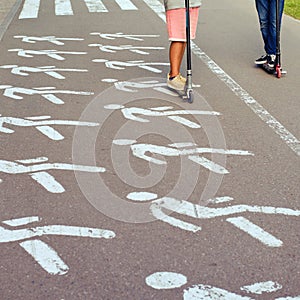 People ride a scooter in the park along a pedestrian crossing