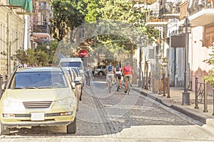 People riding bicycles along the street of the old town. Sunny morning.