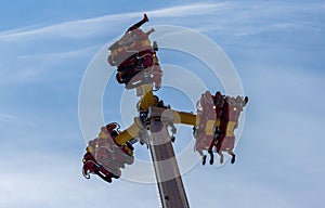 People riding high in the air on a carnival festival ride against blue sky