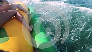 People riding on water inflatable attraction with motor boat Banana on sea