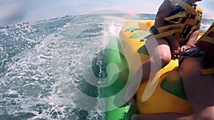 People riding on water inflatable attraction with motor boat Banana on sea