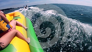 People riding on water inflatable attraction with motor boat Banana on sea