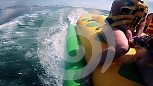 People riding on water inflatable attraction with motor boat Banana on sea