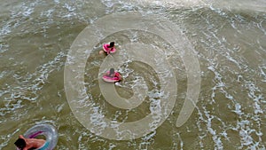 People in rubber rings swim on the waves in the sea. Aerial video