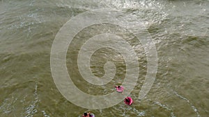 People in rubber rings swim on the waves in the sea. Aerial video