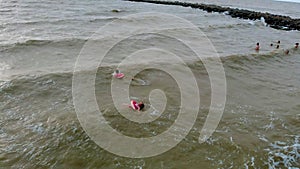 People in rubber rings swim on the waves in the sea. Aerial video