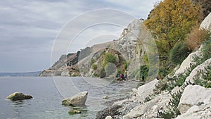 People run along the river. Jogging on the coast. A large river, on the banks of trees and green grass. Around rocks