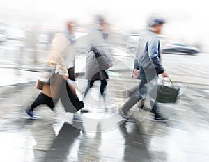 People rushing over pedestrian crossing on rainy day