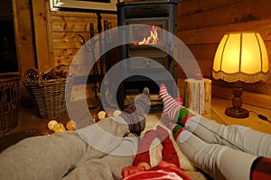 people's feet glowing fireplace, family sitting on floor on white sheepskin, young couple and daughter on Christmas evening