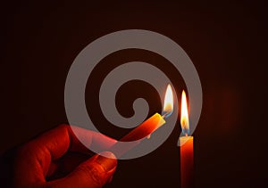 People`s hands are lit by candles in the dark. Design for the background, hand with candle