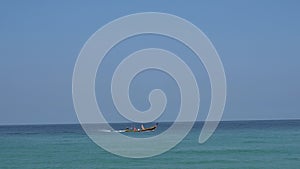 People sail on a traditional Thai boat. View of the horizon, blue sky and green water.