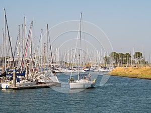 People with sailboat leaving harbor of Colijnsplaat at Oosterschelde, Noord-Beveland, Zeeland, Netherlands