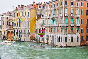 People sailing boats and water taxis beside gothic Venetian buildings on a rainy November day on the Grand Canal waterway, Venice.