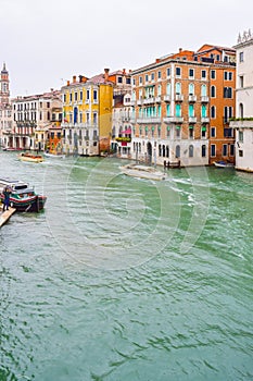 People sailing boats and water taxis beside gothic Venetian buildings on a rainy November day on the Grand Canal waterway, Venice