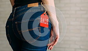 People, sale, consumerism concept. Close up cropped photo of sexual woman`s buttocks wearing blue casual denim pants on gray