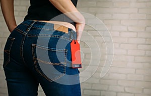 People, sale, consumerism concept. Close up cropped photo of sexual woman`s buttocks wearing blue casual denim pants on gray bric