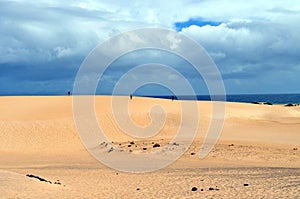 People on sand dunes,ocean and clouds