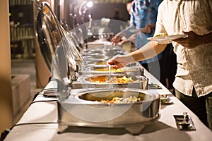 People are scooping food from chafing dishes on the table at the luxury banquet