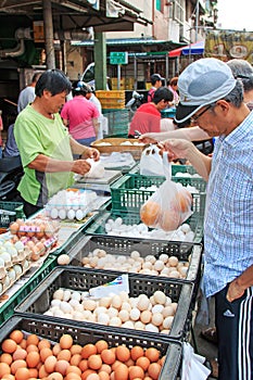 People selling and buying food in a traditional fruit and vegetable market of Taiwan